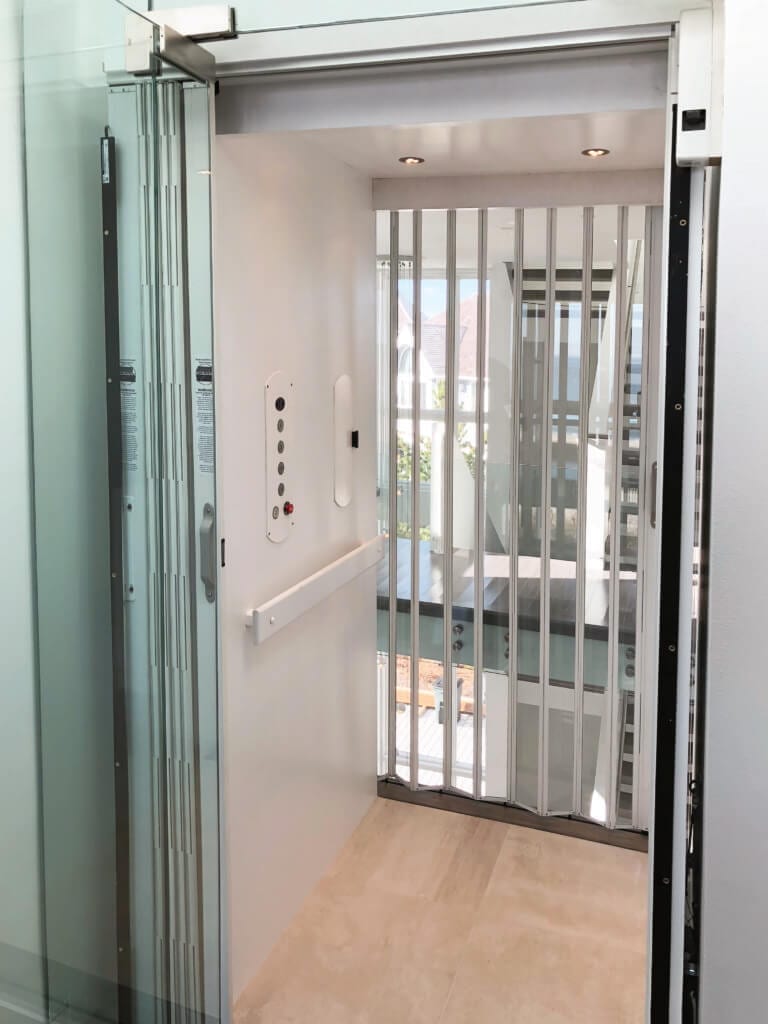 Symmetry Home Elevator with painted white interior, glass door and clear acrylic accordion gate.