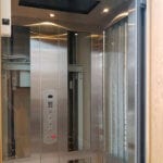 Symmetry Home Elevator in glass and stainless-steel, with wrap around gate installed by Morning Star