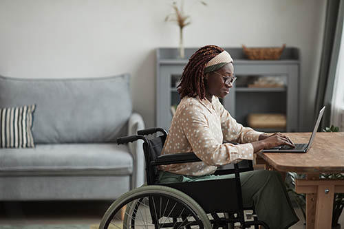 woman in wheelchair on computer in home