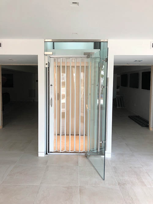 beach house glass elevator lit up white and clear accordion door