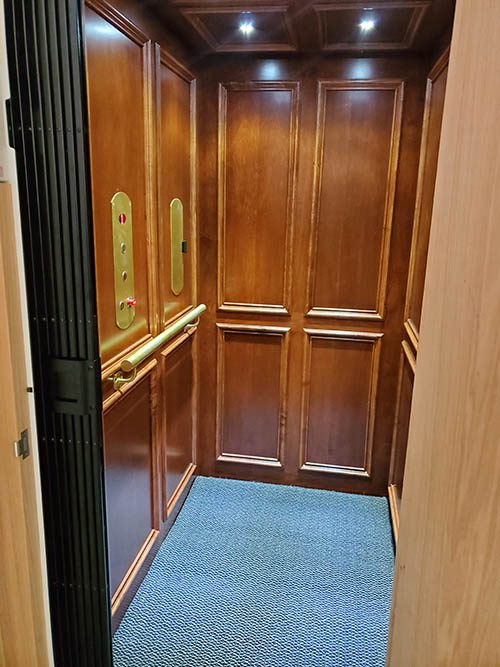 Clean wood residential elevator with blue carpet and LED lights